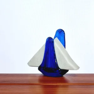 Servilletero artesanal de vidrio azul cobalto con servilletas, exhibido sobre una mesa de madera.