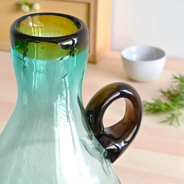Detalle del asa y la boca de la Botella Mexicana Gigante, mostrando la unión artesanal del vidrio y los diferentes tonos de color.