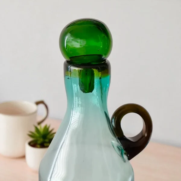 Primer plano de la tapa de vidrio esférica color verde de la Botella Mexicana Gigante, destacando el detalle artesanal del vidrio soplado.