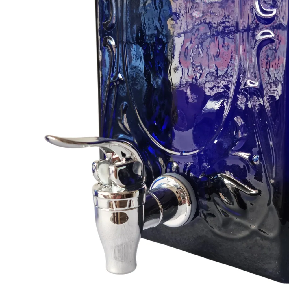 El Impresionante Dispensador de Bebidas de Vidrio Artesanal Azul 3.9L 7 Primer plano de la llave dispensadora de acero inoxidable instalada en el dispensador de bebidas de vidrio azul cobalto labrado.
