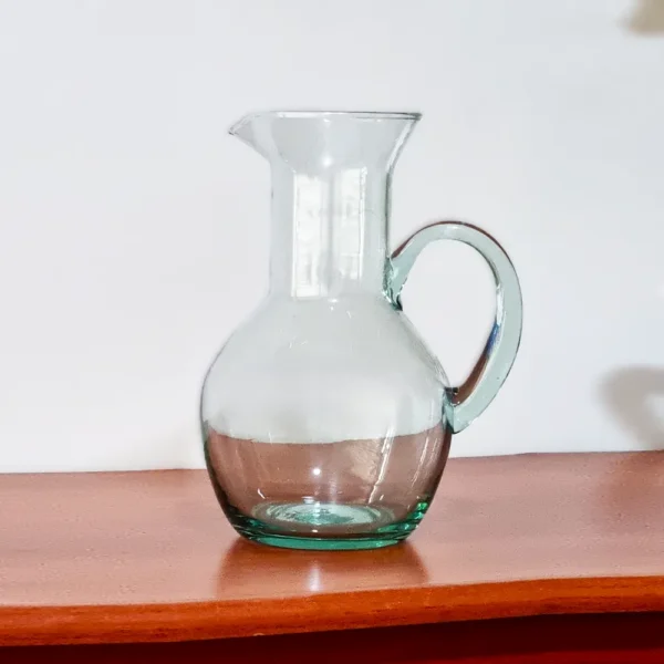 Jarra de vidrio transparente modelo Ánfora de 1.2 litros, exhibida sobre una mesa de madera.