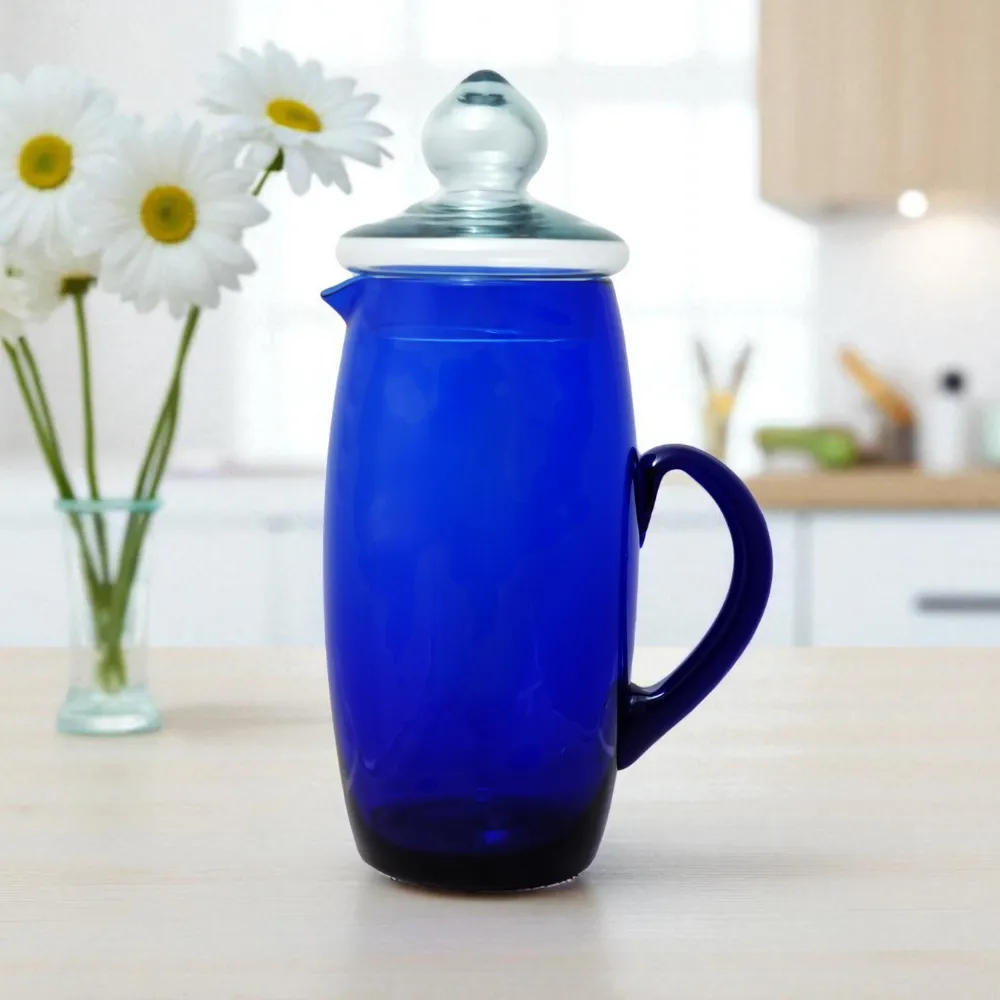 Jarra de vidrio Tamy de 2.1L en color azul cobalto, sobre una encimera de madera en una cocina moderna junto a un florero con margaritas.